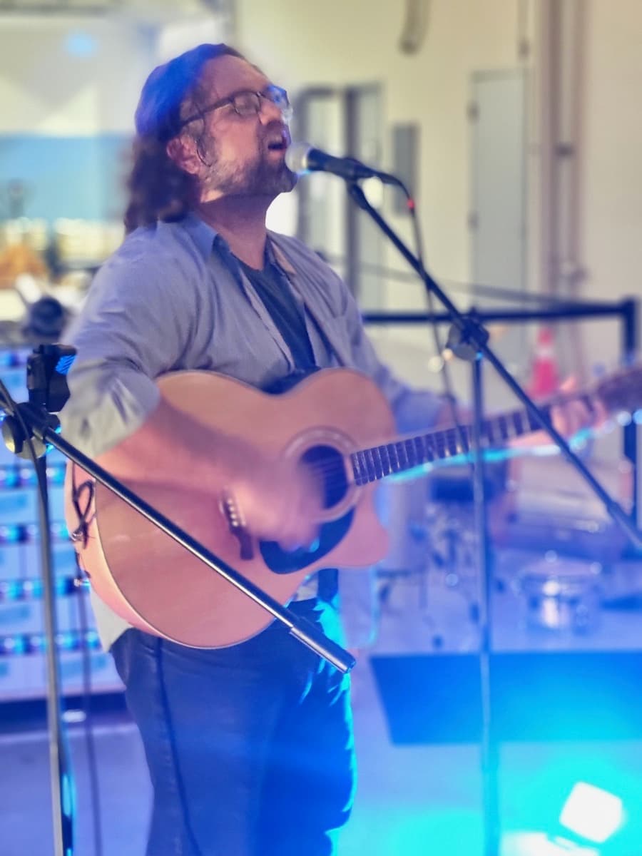 a man playing an acoustic guitar in front of a microphone