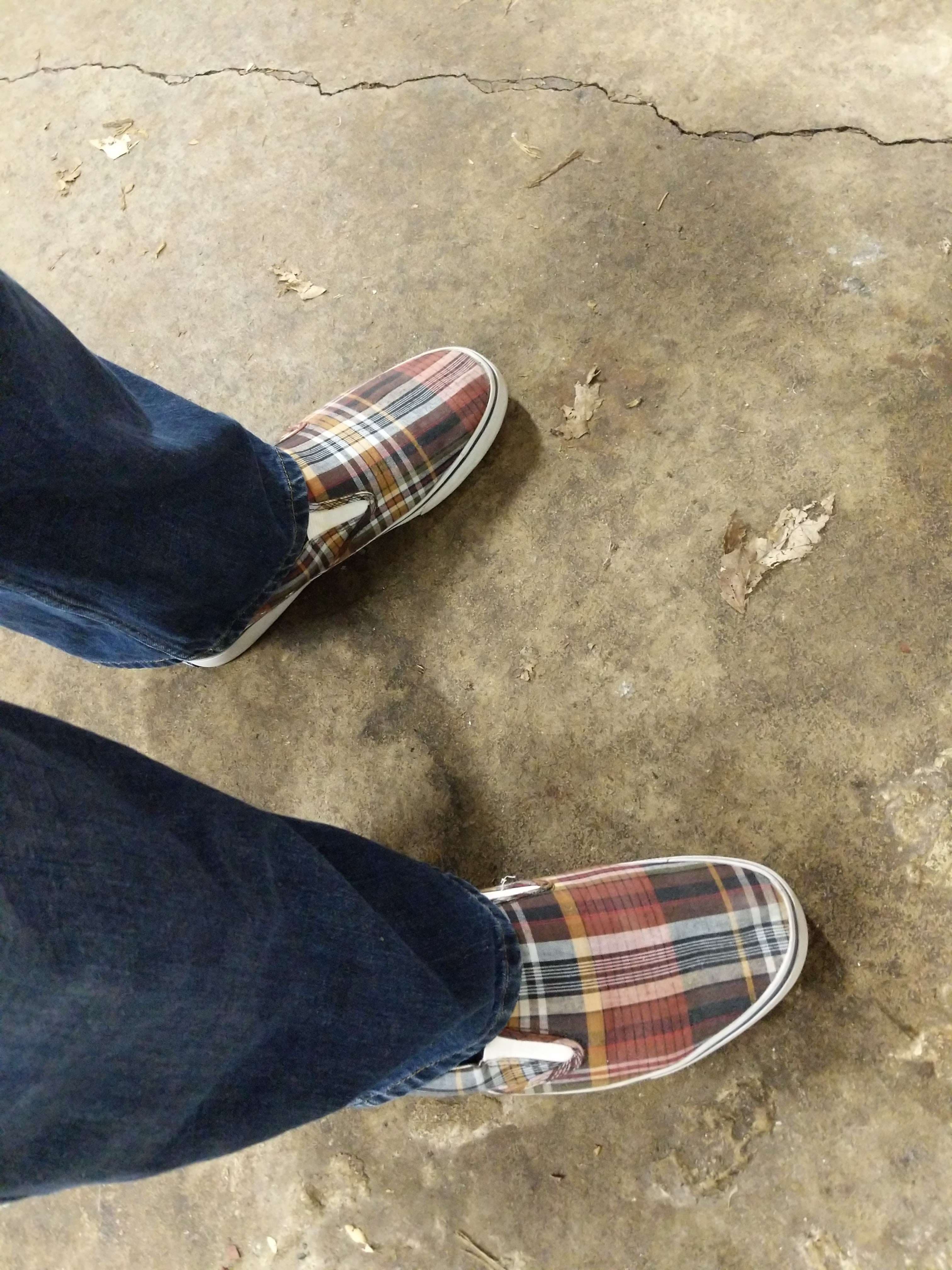 a person standing on a concrete floor in a pair of plaid shoes
